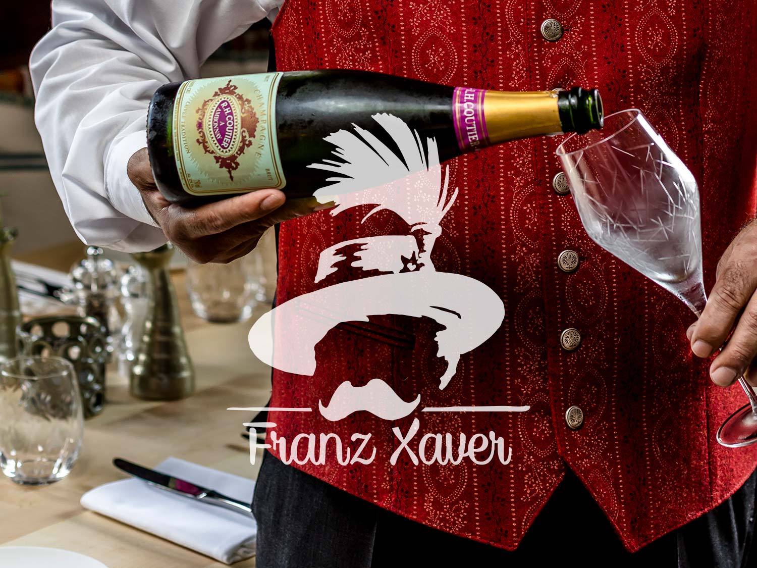 Das Logo vom Wirtshaus Franz Xaver wurde in tranzparentem weiß mittig auf einem Foto eines Sommeliers Gaststätteninnenraums platziert.