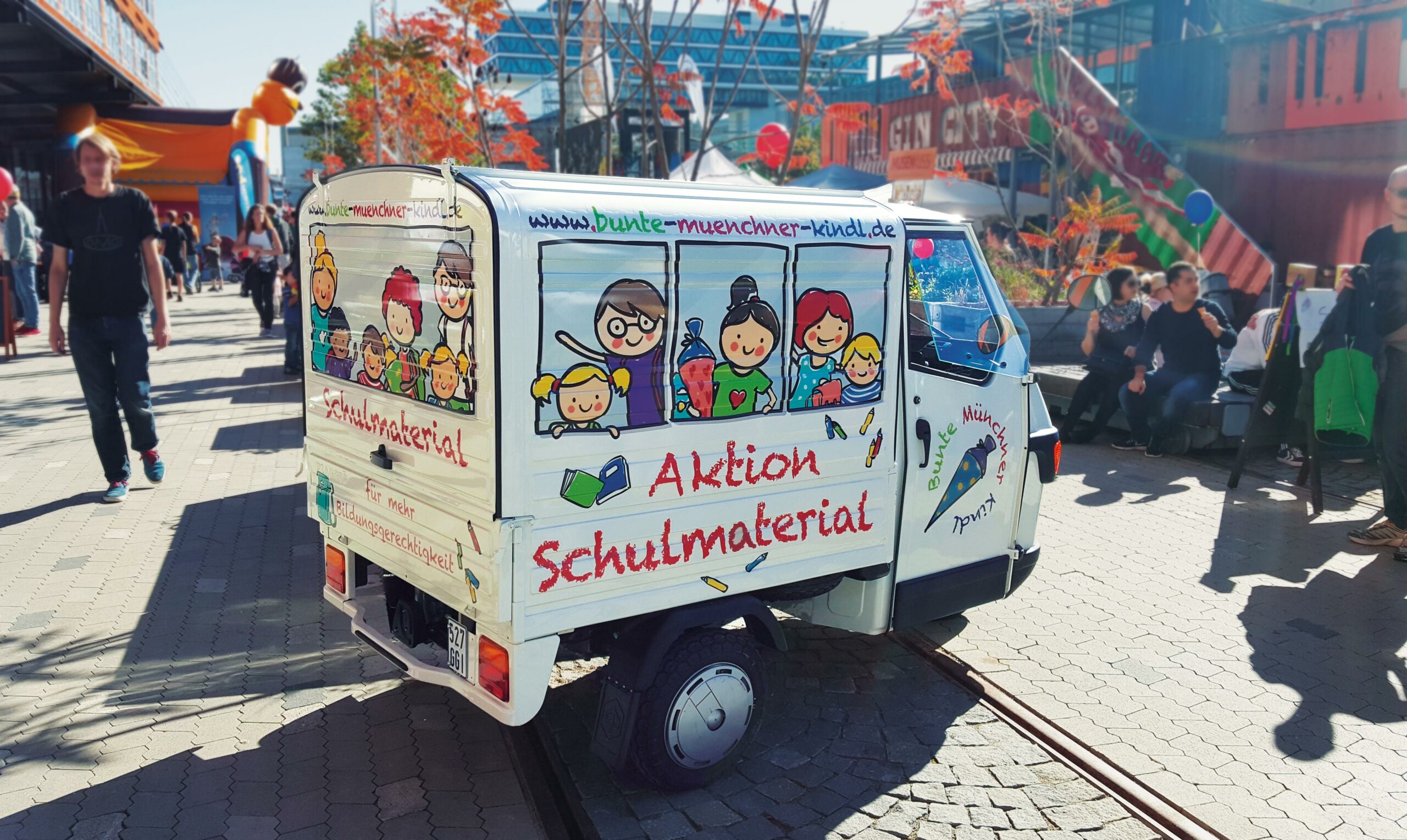 Foto eines mit Illustrationen beklebten Fahrzeugs als Werbemittel für Bunte Münchner Kindl in München. Die bunten Illustrationen geben dem Fahrzeug den Look eines mit Kindern besetzten Schulbusses.