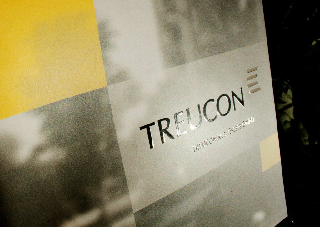 Nahaufnahme des Covers der Imagebroschüre von Treucon Real Estate GmbH Berlin. Das Cover überzeugt mit einer Druckveredelung des Treucon Logos.