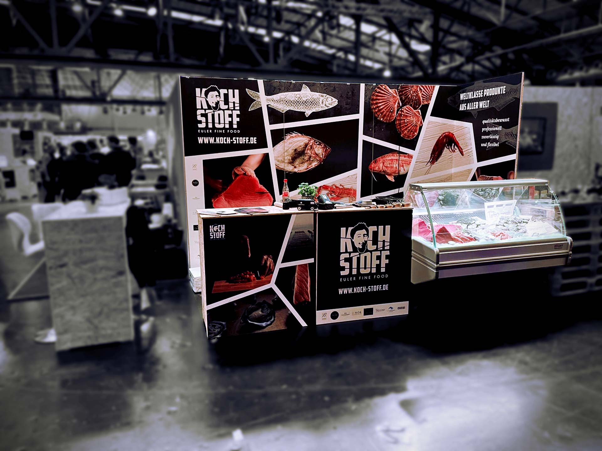 Foto des Messestandes kochstoff. Vorne der Messestand, im Hintergrund sieht man die Messehalle